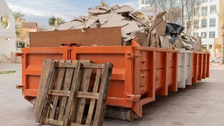 Orange roll-off bins loaded with construction debris