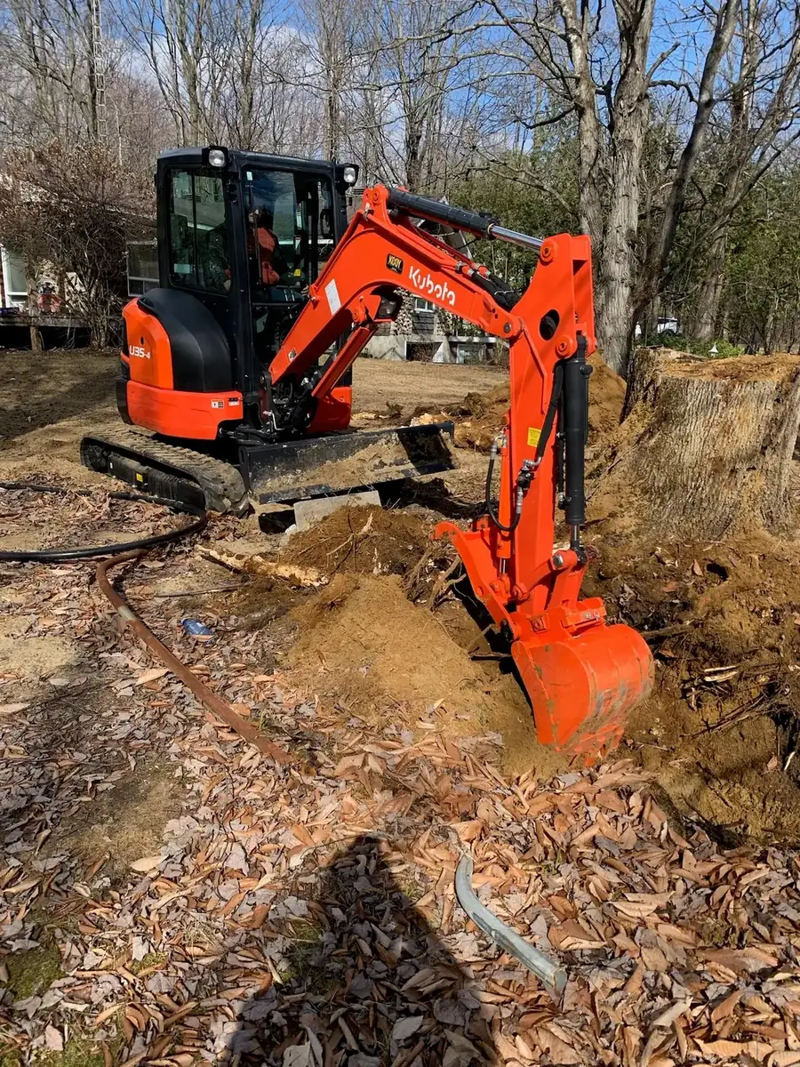 Mini excavator digging on a wooded lot